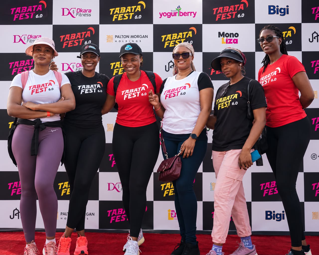 Tabata Fest attendees posing at the sponsor backdrop